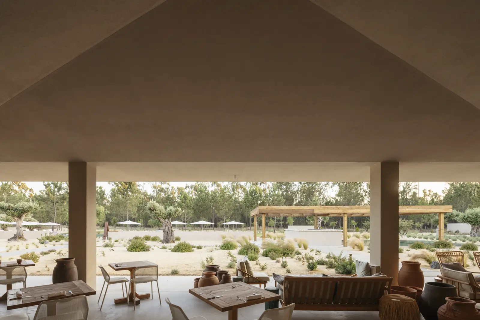 Spatia Comporta hotel restaurant terrace with wooden tables and views to the pool and pines.